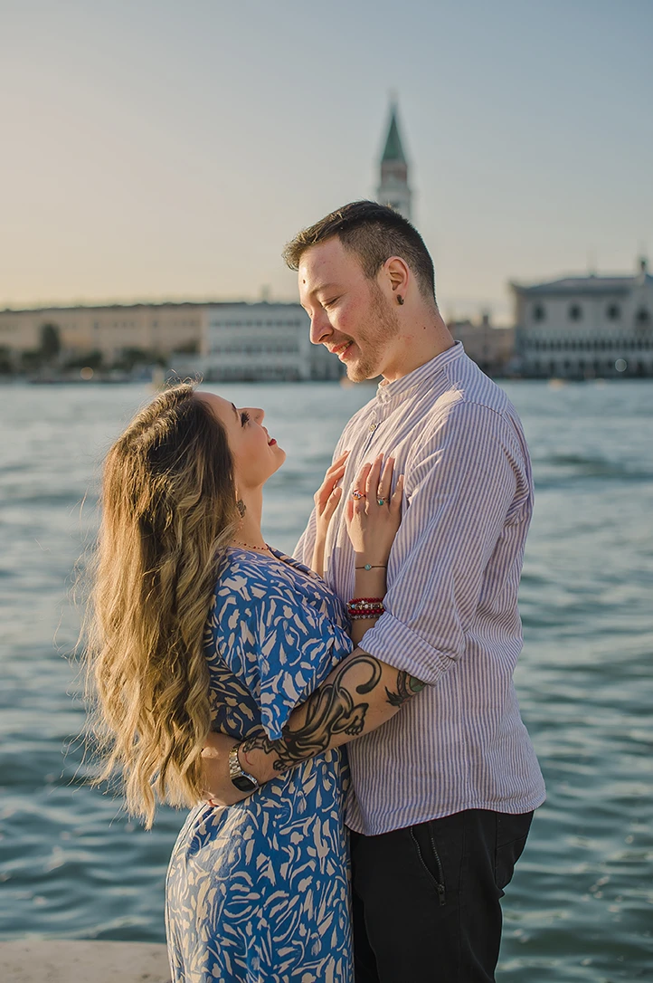 Maria and Barth, hold hands and stare into each other's eyes with affection, the golden hour sunlight softly illuminating their faces.