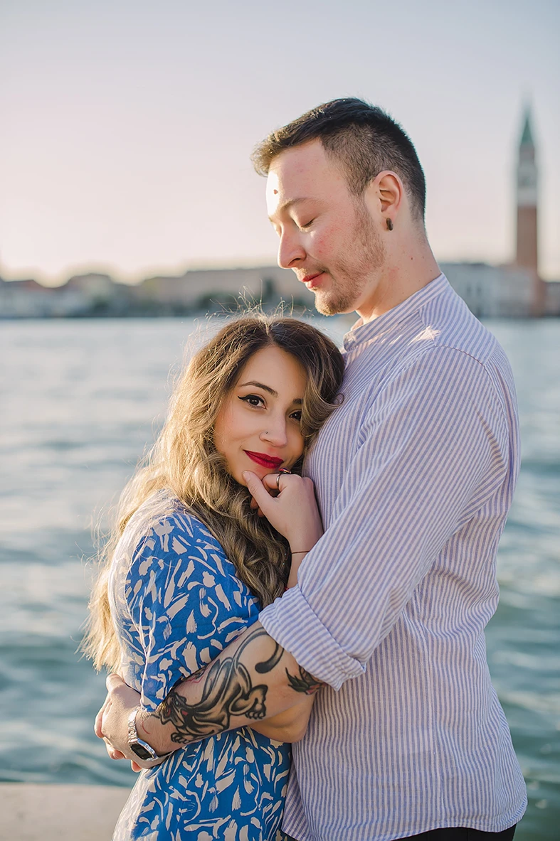 Maria and Barth, hold hands and stare into each other's eyes with affection, the golden hour sunlight softly illuminating their faces.