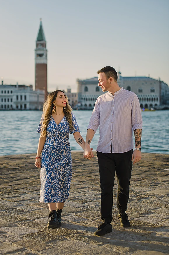 Maria and Barth, hold hands and stare into each other's eyes with affection, the golden hour sunlight softly illuminating their faces.