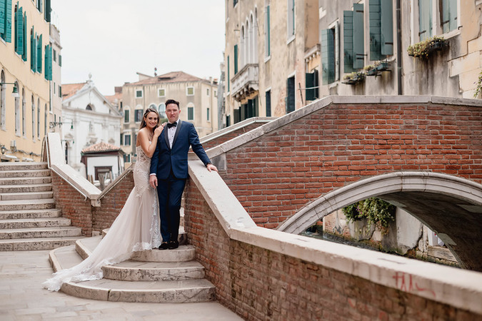 A married couple stand in the center of the image early in the morning in Venice