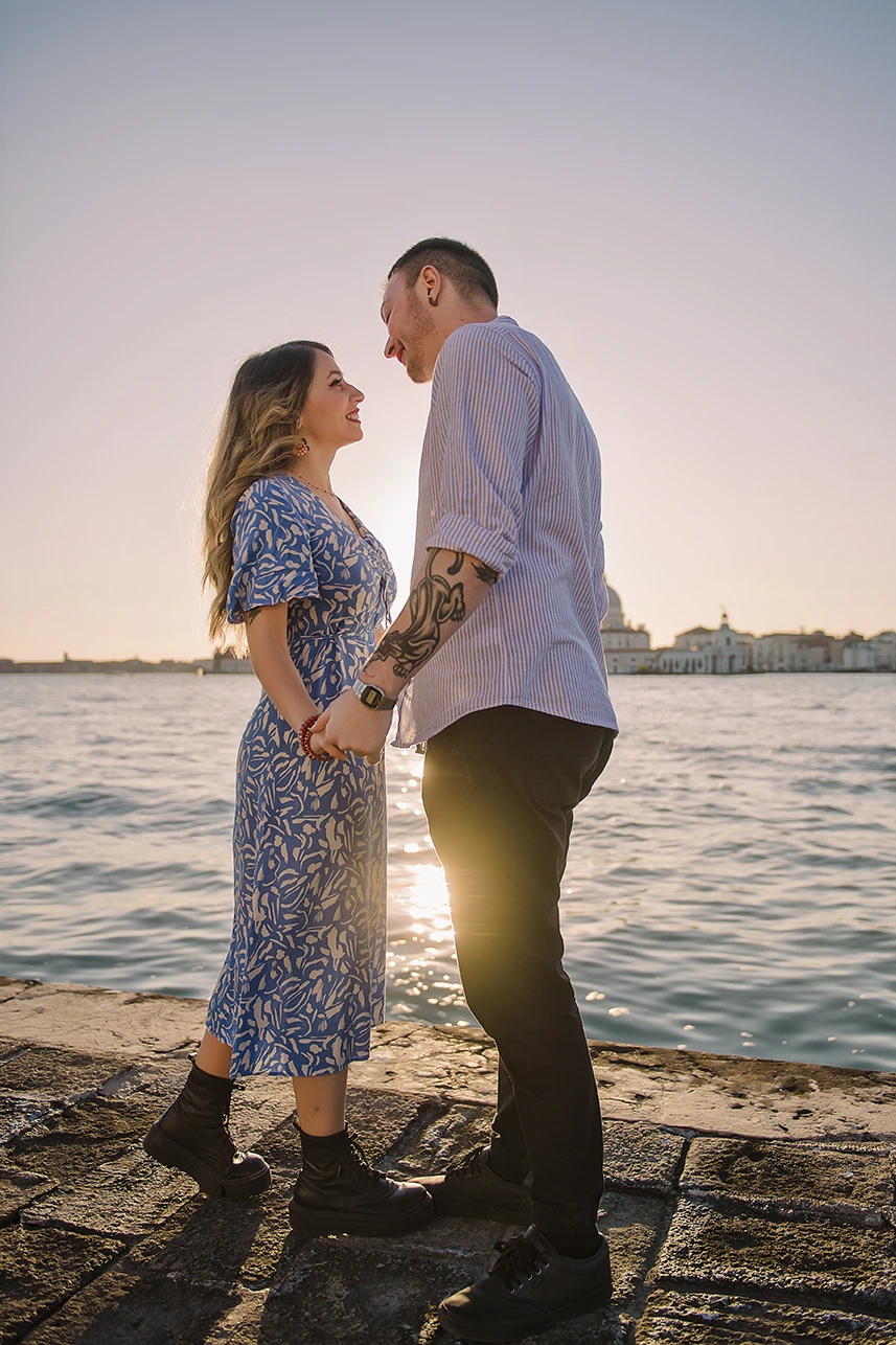 An intimate kiss of Barth and Maria as they stand by the Grand Canal, their silhouettes framed against the twinkling lights of evening Venice