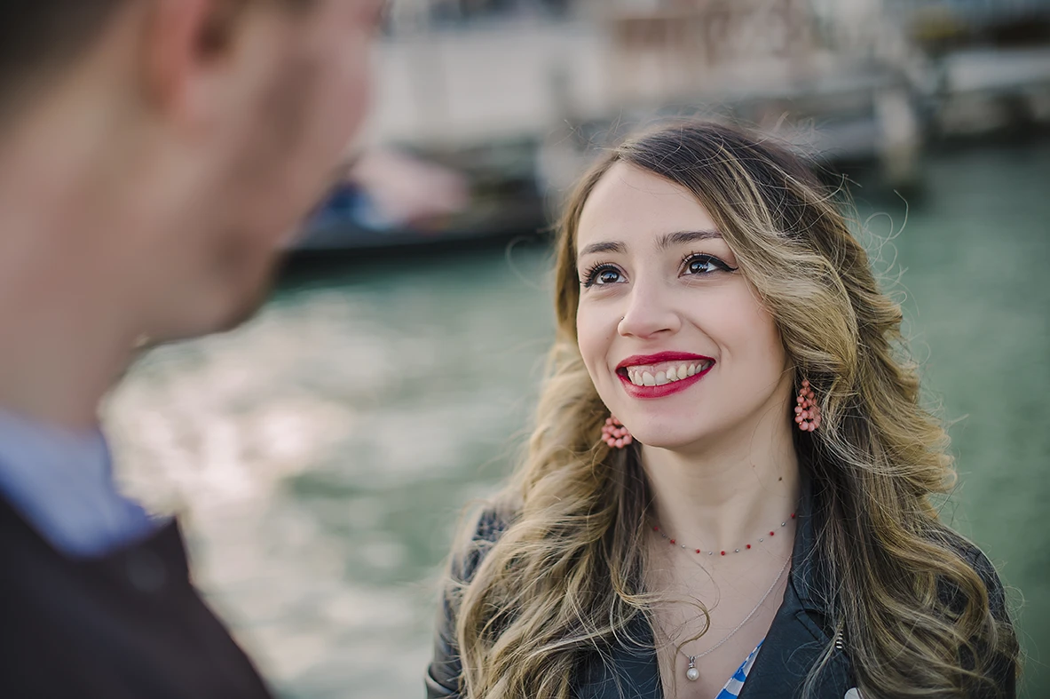 A candid shot capturing the couple's spontaneous dance, with Maria's flowing dress and the serene, amber-tinted sky of Venice creating a timeless scene.
