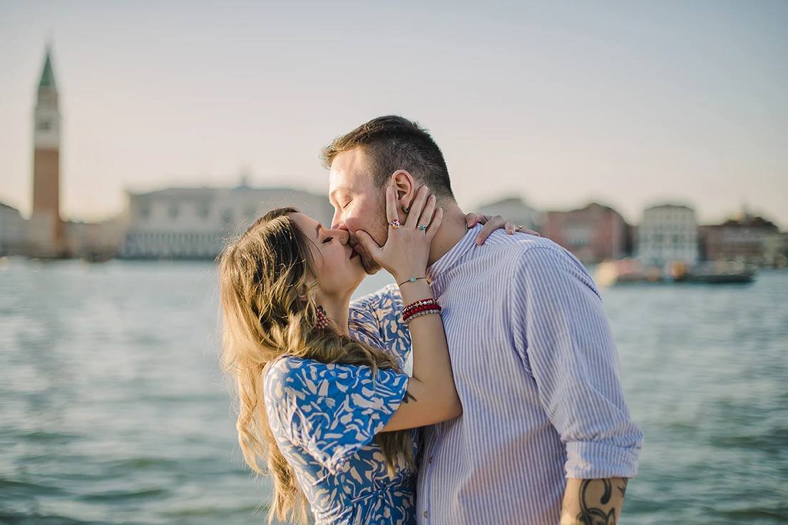 The newly-engaged couple embrace tightly in San Giorgio Maggiore, their expressions a mix of shock and delight.