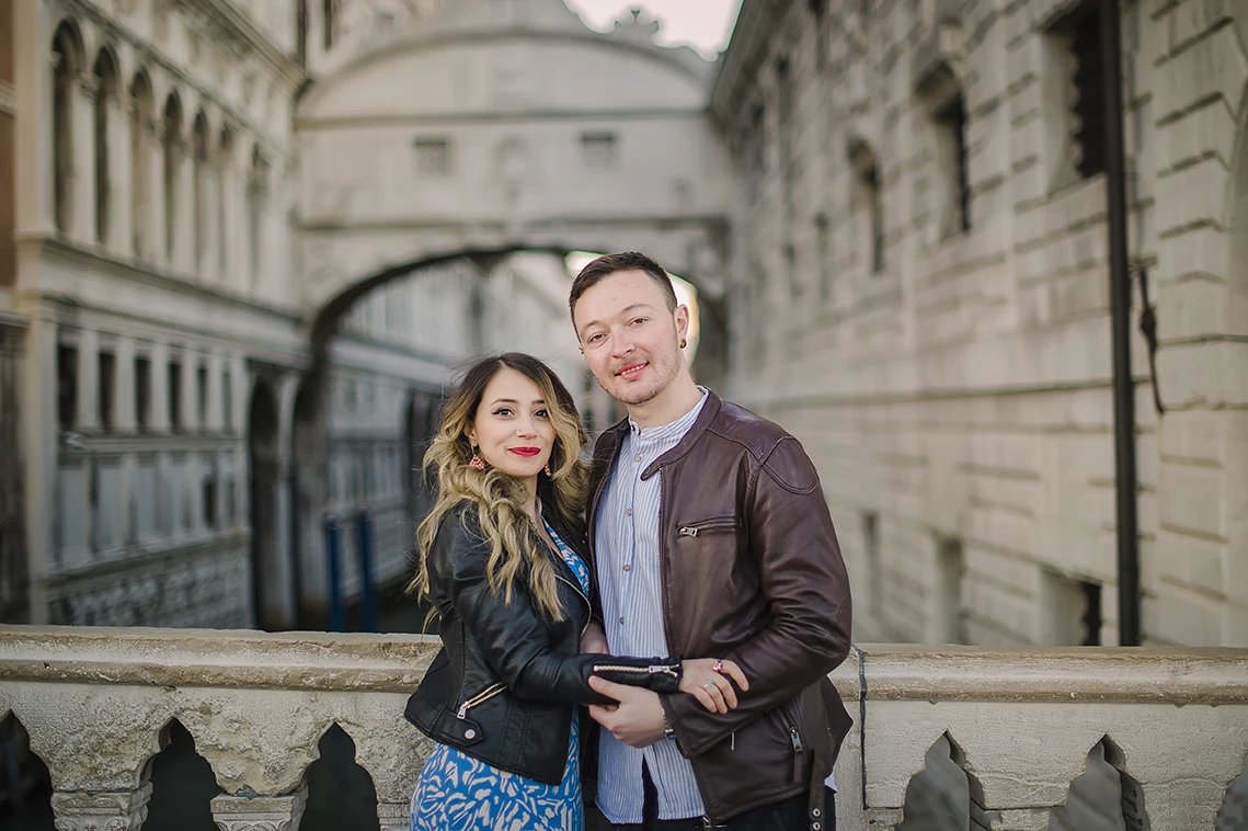 A candid shot capturing the couple's spontaneous dance, with Maria's flowing dress and the serene, amber-tinted sky of Venice creating a timeless scene.