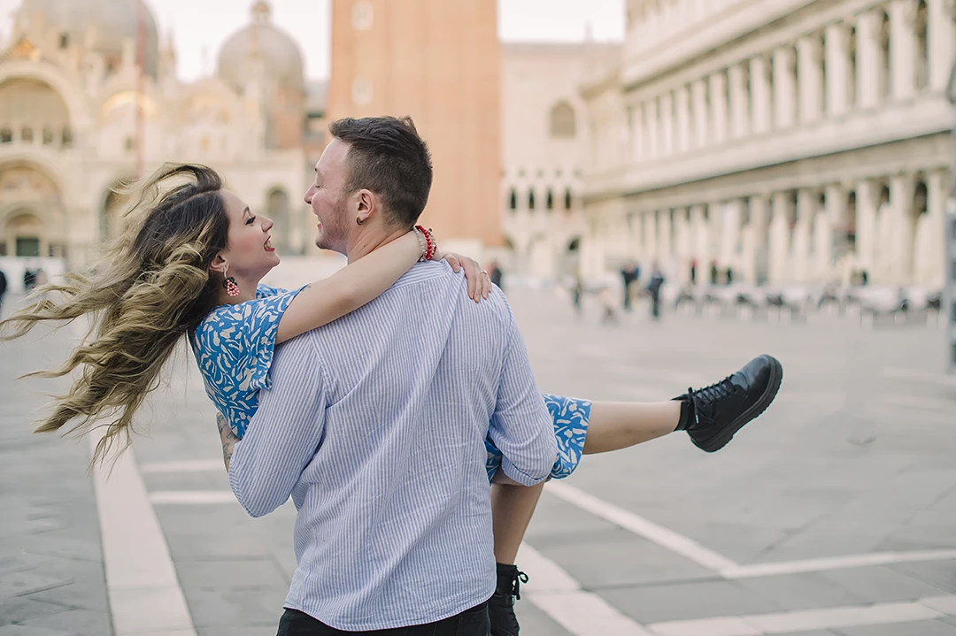 The fiancés share a gentle kiss  with the historic buildings of Venice 