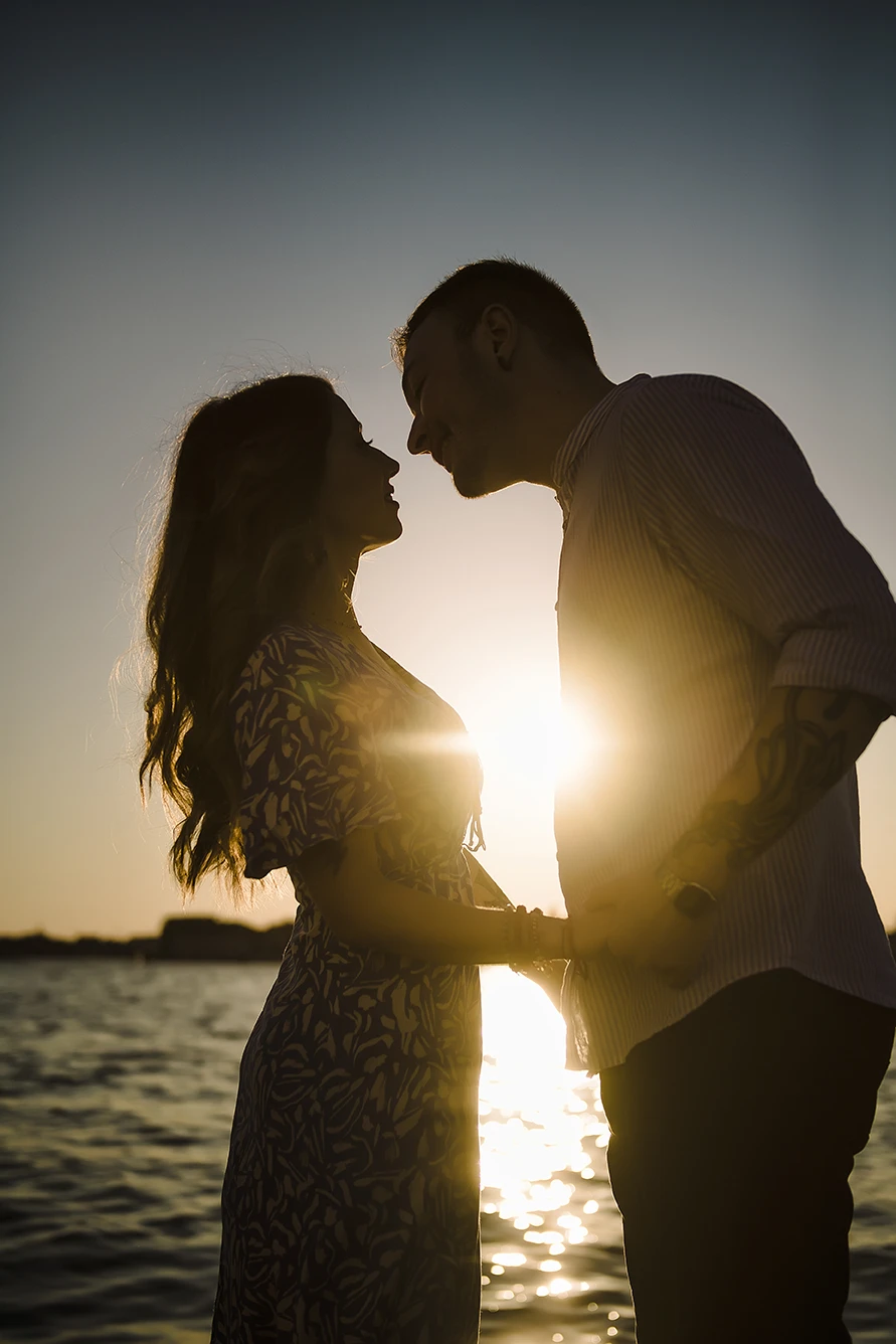 An intimate kiss of Barth and Maria as they stand by the Grand Canal, their silhouettes framed against the twinkling lights of evening Venice