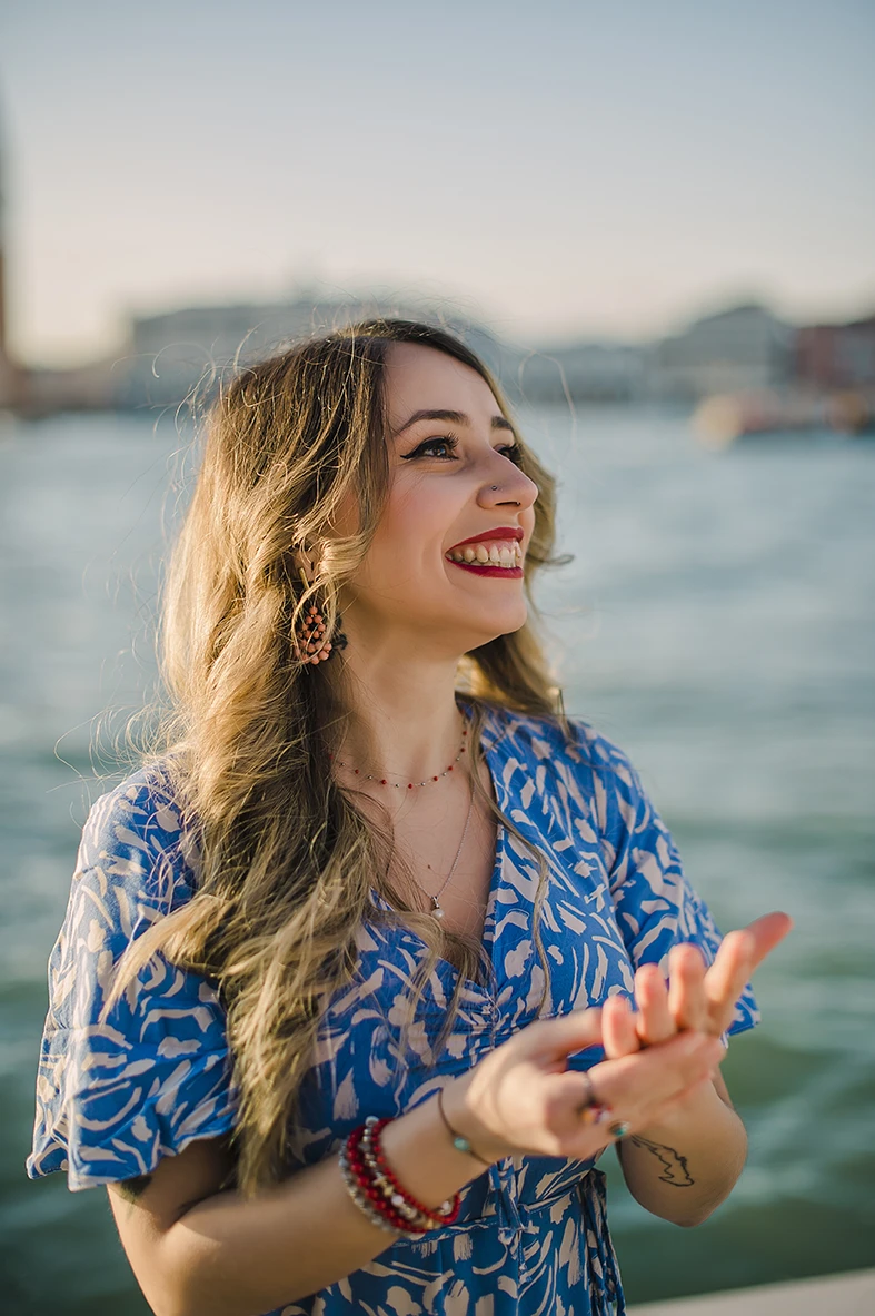 Close-up of Maria's hands as she lovingly touches Barth's shoulder while looking down at the ring with teary eyes of happiness against the backdrop of the Venice lagoon.