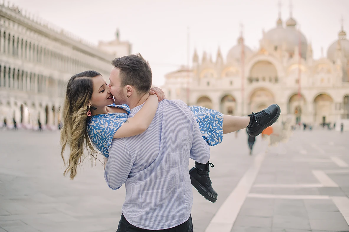 The fiancés share a gentle kiss  with the historic buildings of Venice 