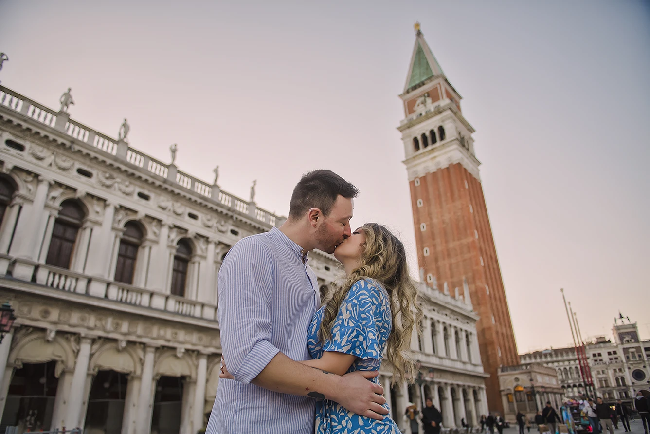 The fiancés share a gentle kiss  with the historic buildings of Venice 