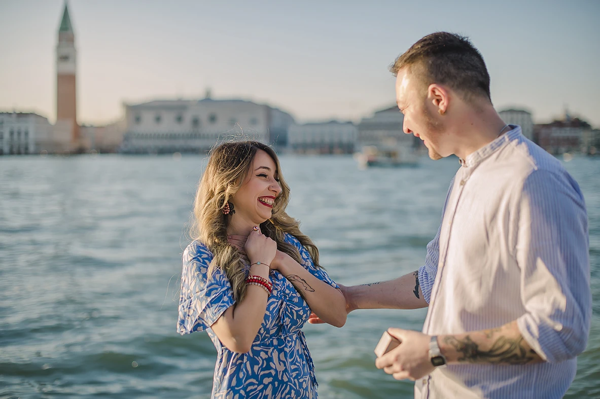The newly-engaged couple embrace tightly in San Giorgio Maggiore, their expressions a mix of shock and delight.