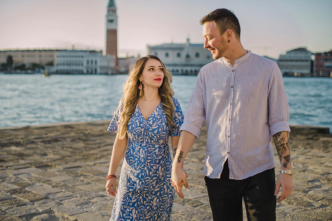 Maria and Barth, hold hands and stare into each other's eyes with affection, the golden hour sunlight softly illuminating their faces.