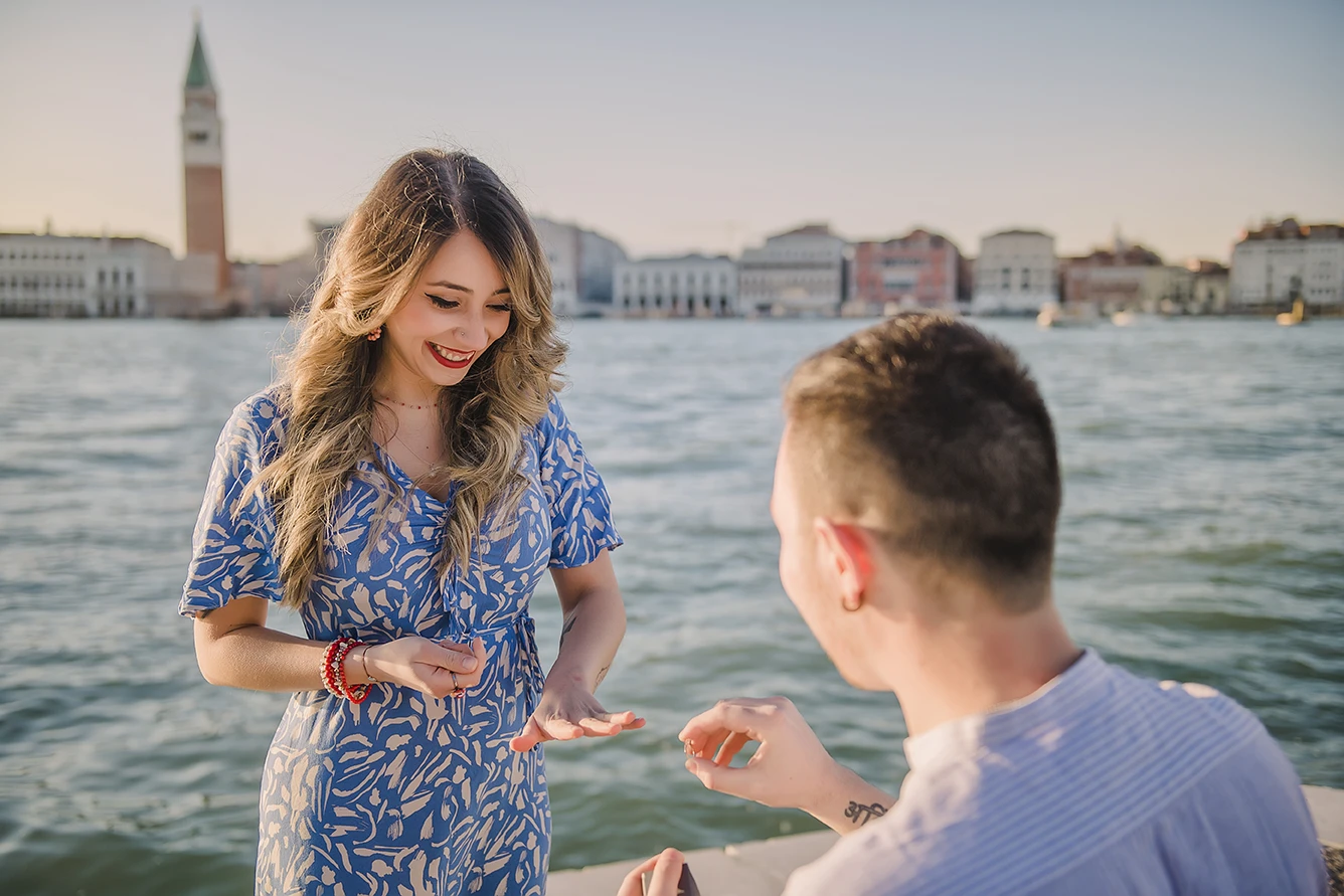 The newly-engaged couple embrace tightly in San Giorgio Maggiore, their expressions a mix of shock and delight.