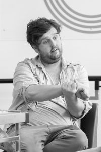 The images shows Daniel Burgess talking to someone out of shot in a rehearsal process