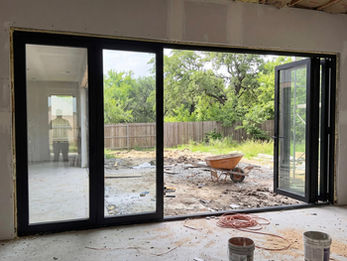 Interior view of large glass bifold door system connecting living room to backyard