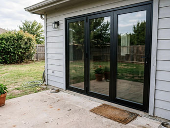Black framed sliding patio doors on modern exterior home with clean siding