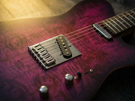 Close-up of a Telecaster-style guitar with a stunning quilted maple top and a translucent purple finish.