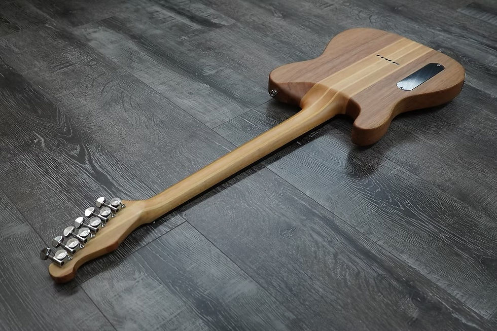 Back view of a natural wood Telecaster-style electric guitar on a dark gray wood-grain floor.
