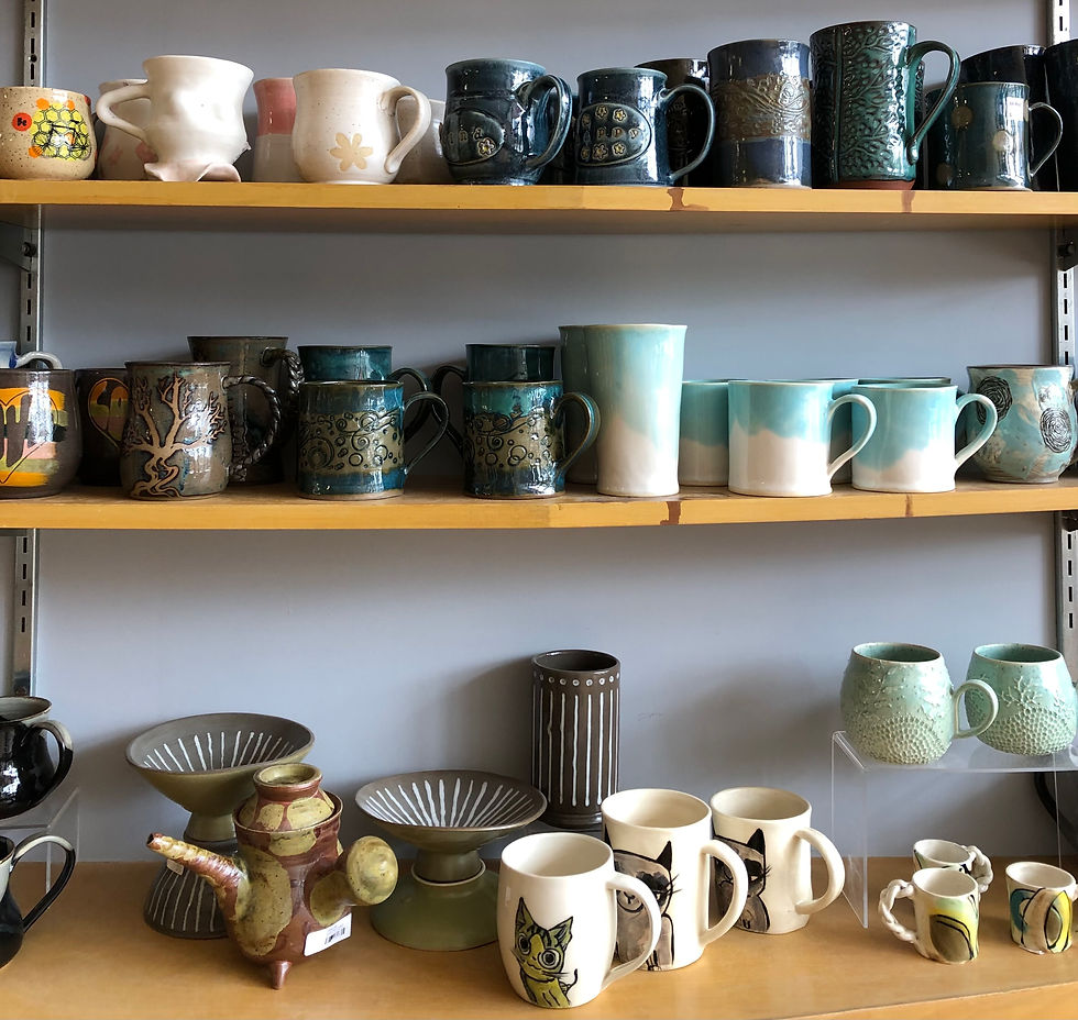 Three shelves filled with handmade ceramic mugs.