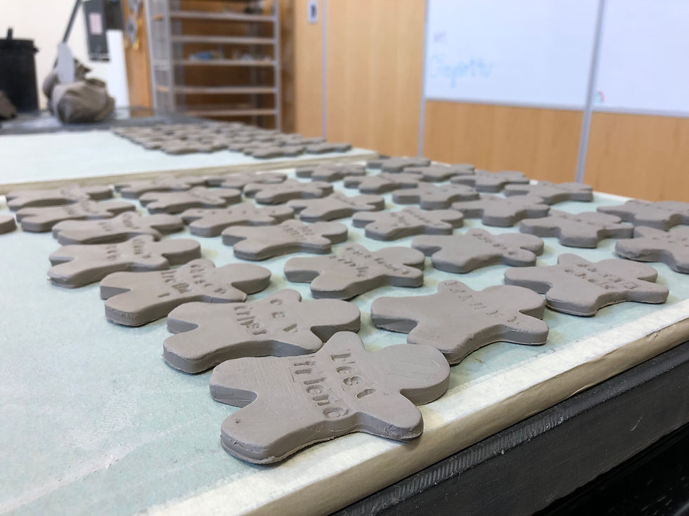 A tray of gingerbread person shaped clay tiles with words stamped into each one.