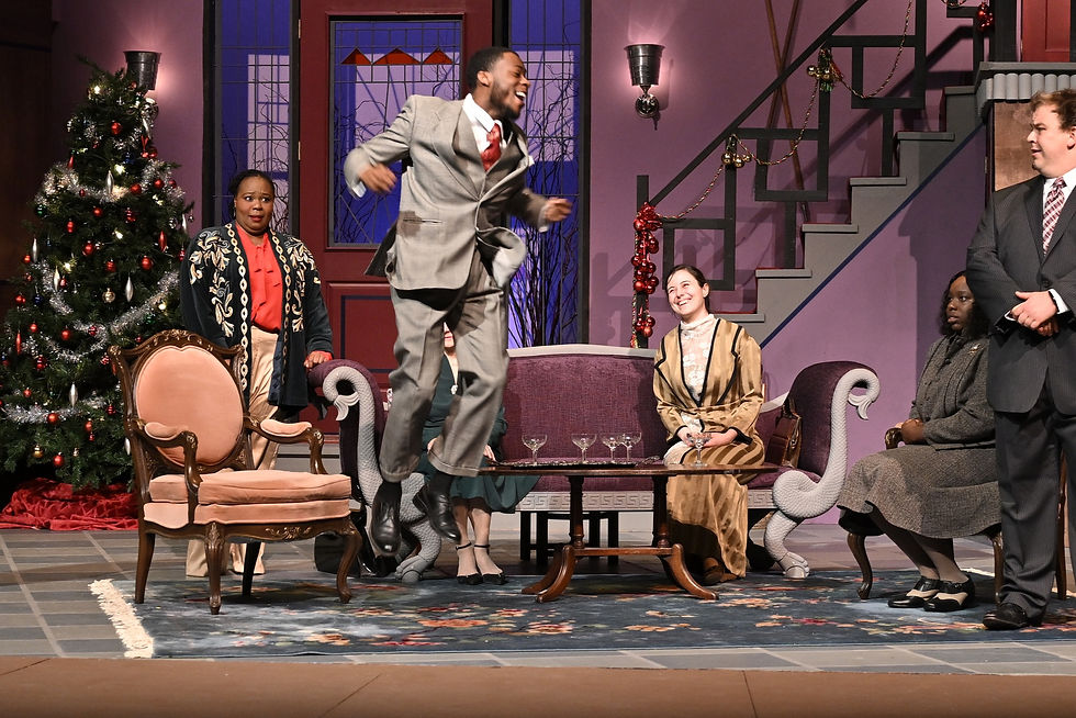 Actors on stage in a Christmas mansion watch a man jump in the air with joy.
