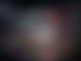 Close-up, shallow-depth-of-field photograph of an AMD processor seated on a motherboard, with fine gold pins and surrounding circuitry in focus, set against a softly blurred, cool gray background, while the AMD logo appears prominently above as clean white lettering with a red mark, creating a sleek, minimal tech editorial look.