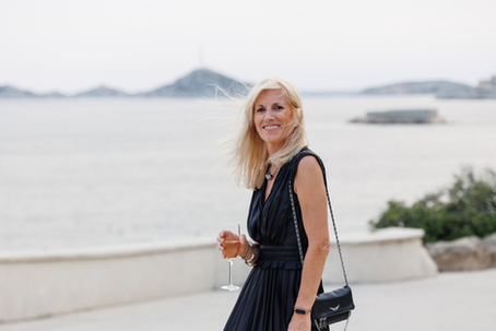 Woman holding a glass with in background view of the coast. To show that style beyond age
