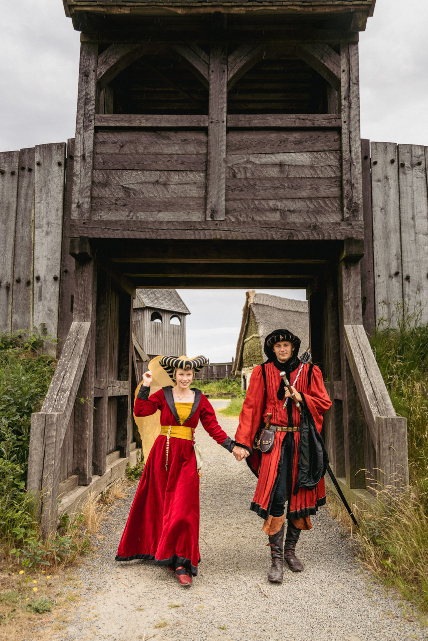 Bride and groom in medieval costumes walking through the historic streets of Bornholm, Denmark