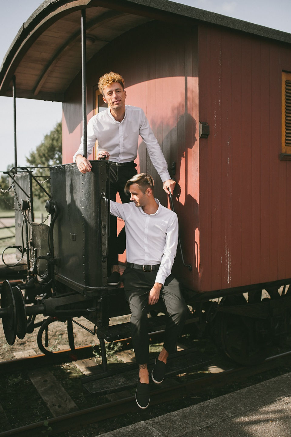 LGBT couple posing at the old train while they eloped in Denmark to their same sex marriage