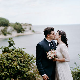 A couple kissing in the front of the natural beauty that Stevens Klint has to offer, a stunning all-natural wedding venue abroad by the Old Hojerup Church.