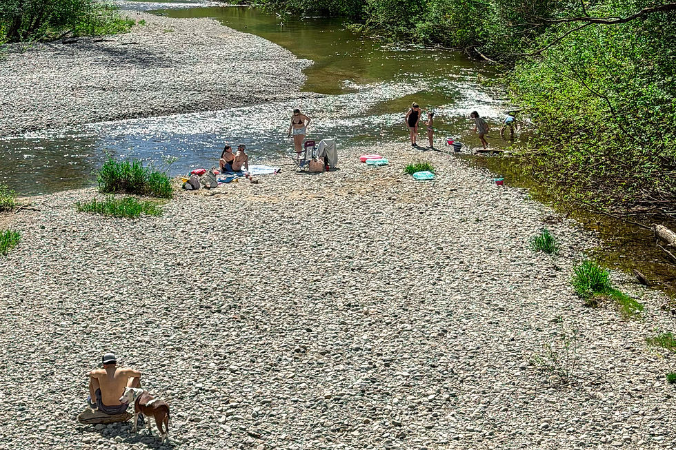 People relaxing on a rocky riverbank along the Coquitlam River in Port Coquitlam