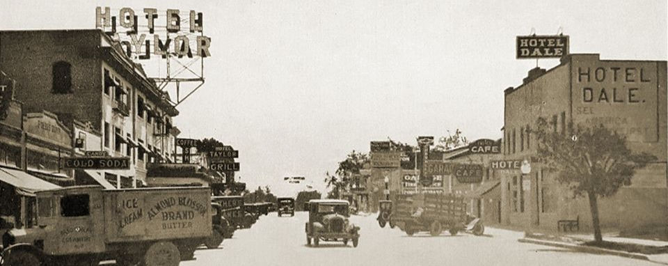 Old photo of downtown Paso Robles street with cars and business signs.
