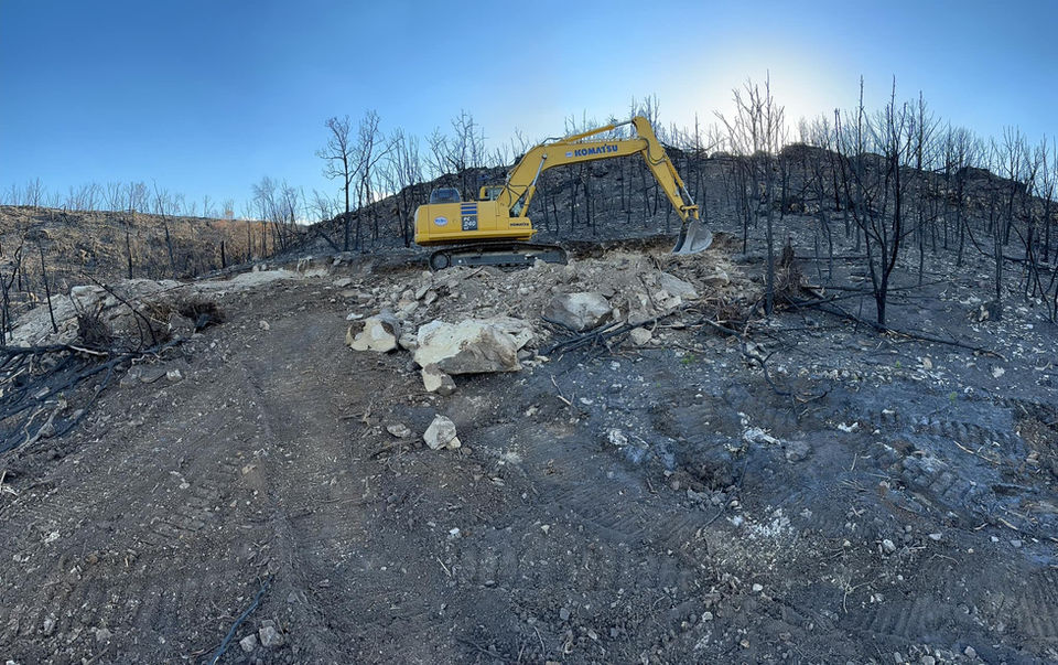 Large excavator moving boulder on Central Texas ranch