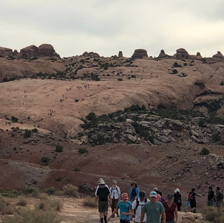 Approaching the steep rock face behind many hikers on Delicate Arch Trail.