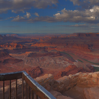 View from Dead Horse Point State Park with brown, red and pink rock formations and the Colorado river flowing through the canyon.