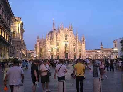 Night time at the Milan Duomo, many people walking along the piazza.