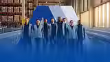 Diverse team of True North Logistics Solutions delivery professionals standing together inside a modern distribution warehouse.