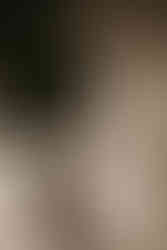 a portrait of anjuli in warm sepia tones, smiling sweetly with her kinky straight extensions worn in a messy bun. the image looks vintage.