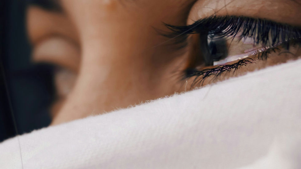 Close-up of a person's eyes, partly covered by a white cloth. The gaze is intense, suggesting contemplation or emotion.