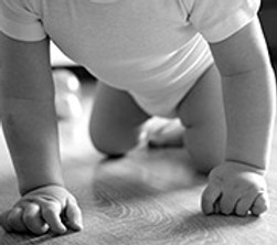 Kinderphysiotherapie suesses baby im niedrigen winkel das auf dem boden kriecht in Graustufen