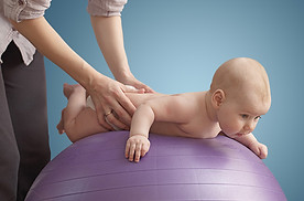 Kinderphysio frau massiert ihr baby auf einem lila ball blauer hintergrund