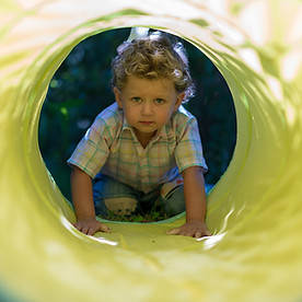 Kinderphysiotherapie Kleinkind Junge der durch Tunnel krabbelt