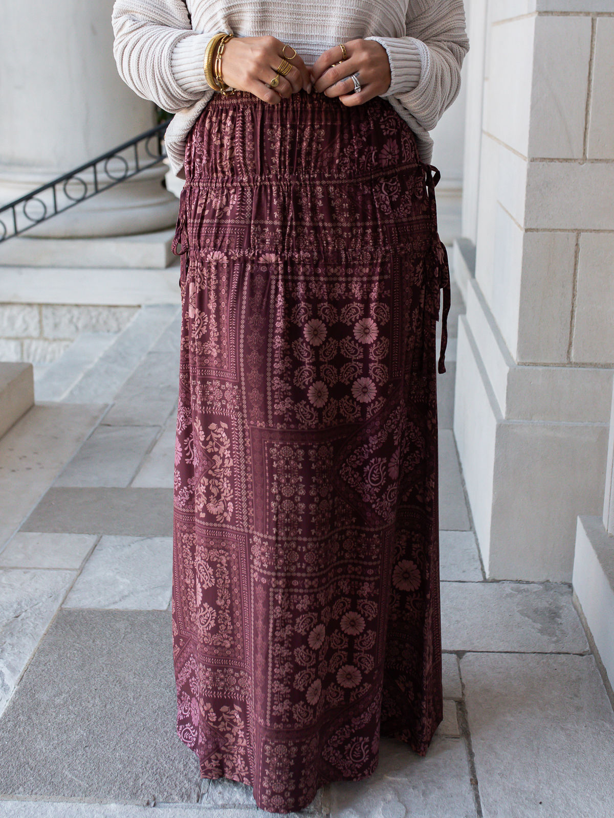 Wine floral maxi skirt featuring a pink paisley patchwork print, smocked waistband, and side tie details.