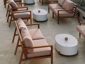 Outdoor all weather furniture with solid teak sofas, weather-resistant cushions, and oval concrete coffee tables on a villa patio.
