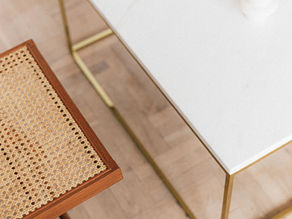 Close-up of woven rattan webbing bench seat and white marble top coffee table with brass legs.