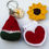 Thumbnail: Handmade crochet accessories including a watermelon slice keychain, sunflower alligator clip, and red heart book magnet.
