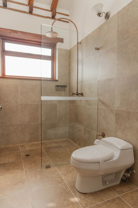 Baño moderno con inodoro, ducha de cristal y azulejos