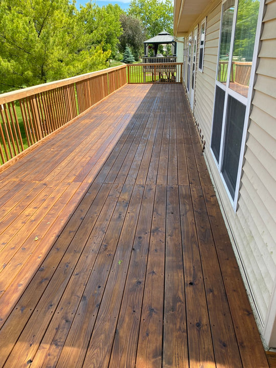 This long-run cedar deck, stained to perfection, hugs the house with fresh handrail balusters for a polished look. Built to last, it wraps around for seamless outdoor flow.