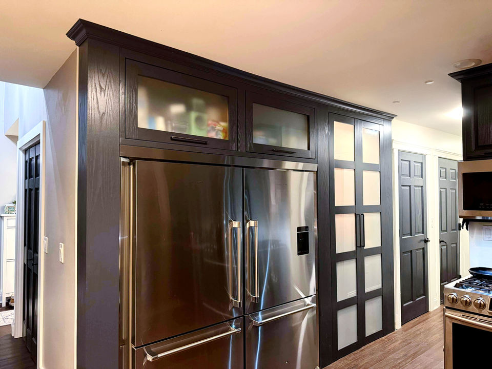 Double-door fridge with custom frosted glass cabinets and frosted glass pantry with crown moulding. 
