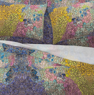 Top view of the Kaleidoscape sheet set with layered flat and fitted sheets and accent pillows