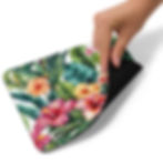 Hand placing mouse on the floral mouse pad to demonstrate size and usability.